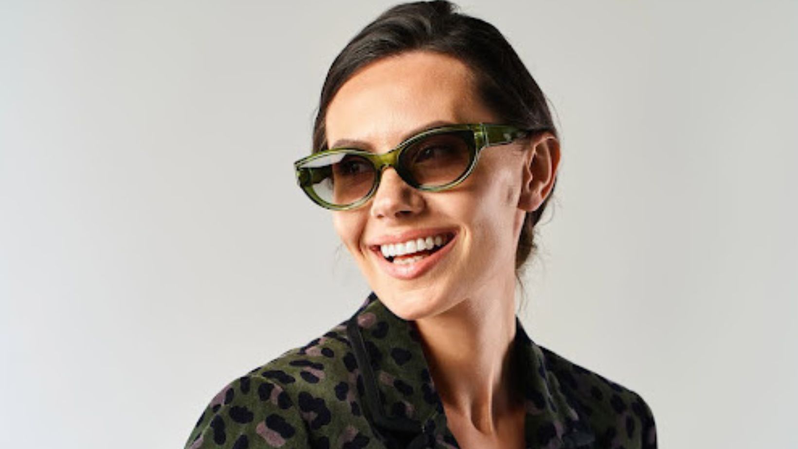 A woman wearing sunglasses while smiling and exuding confidence
