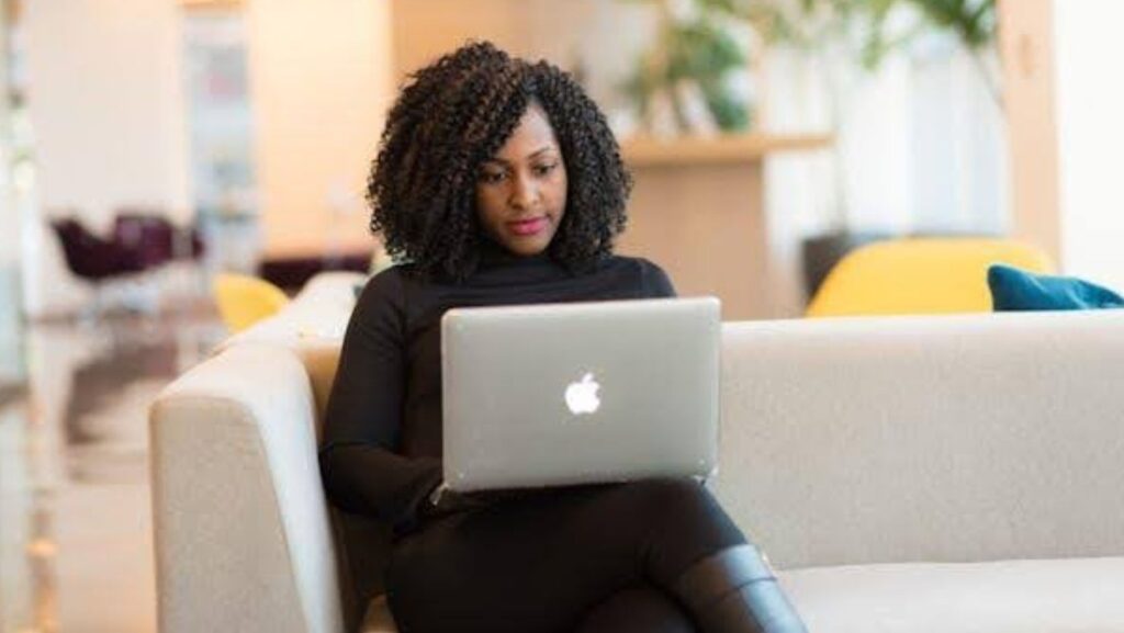 A woman sitting on a sofa, holding a laptop