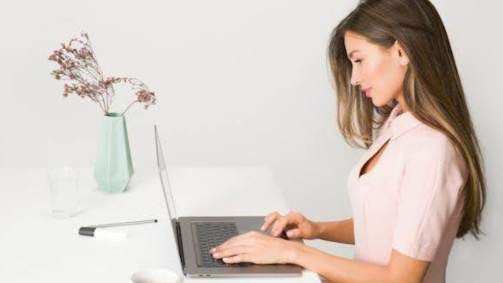 A woman dressed in pink using a laptop