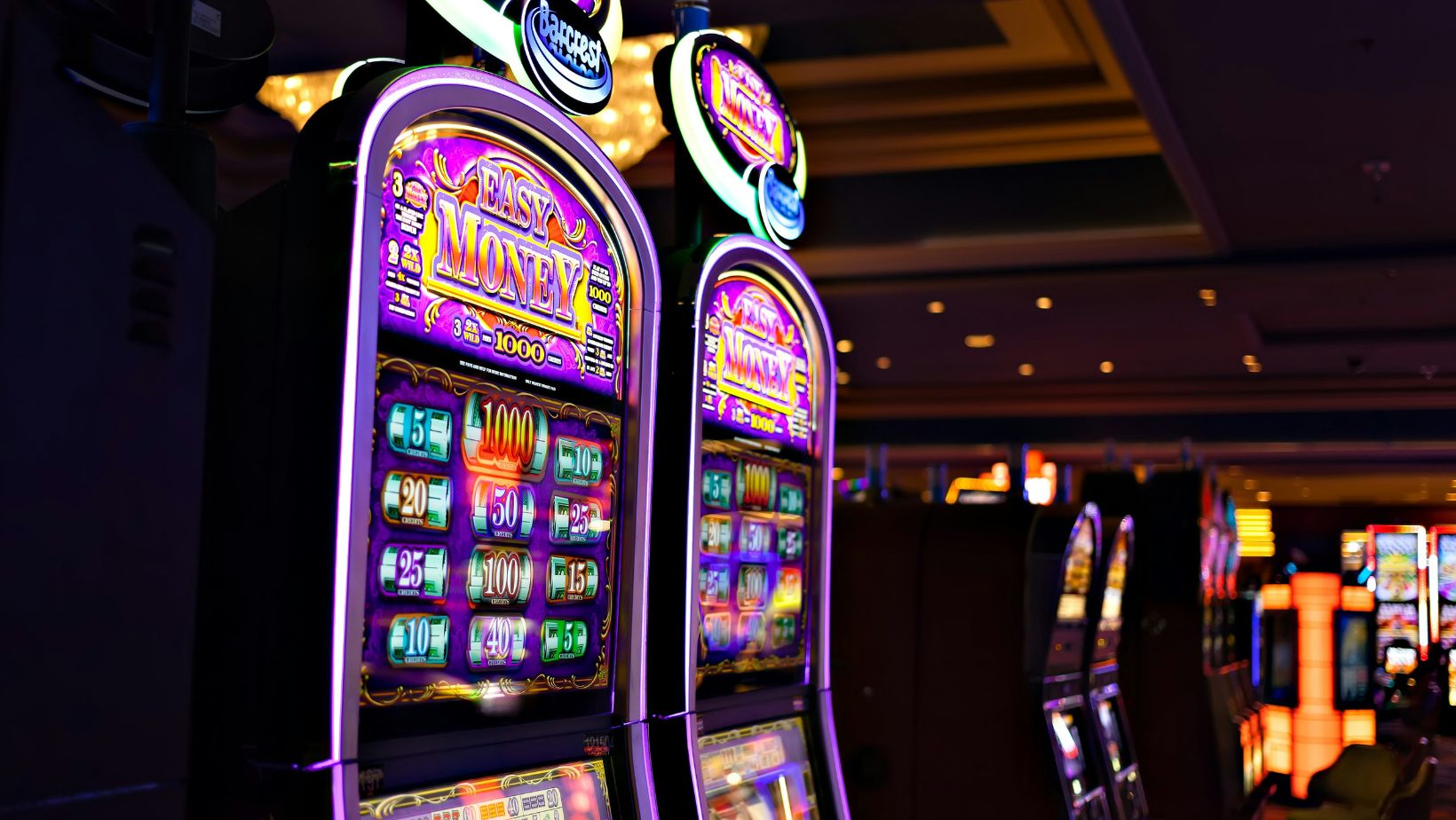 Colorful slot machines lined up inside a casino with bright illuminated screens